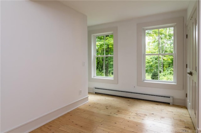 spare room featuring light hardwood / wood-style flooring, a baseboard radiator, and a healthy amount of sunlight