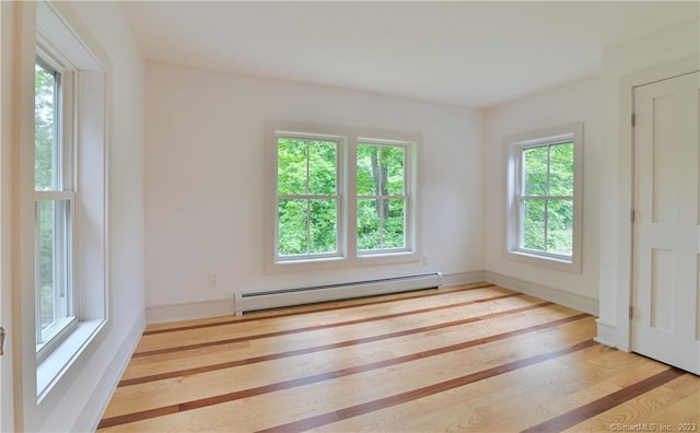 unfurnished room with a baseboard heating unit and light hardwood / wood-style flooring