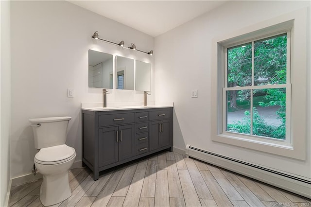 bathroom with a baseboard radiator, toilet, plenty of natural light, and vanity