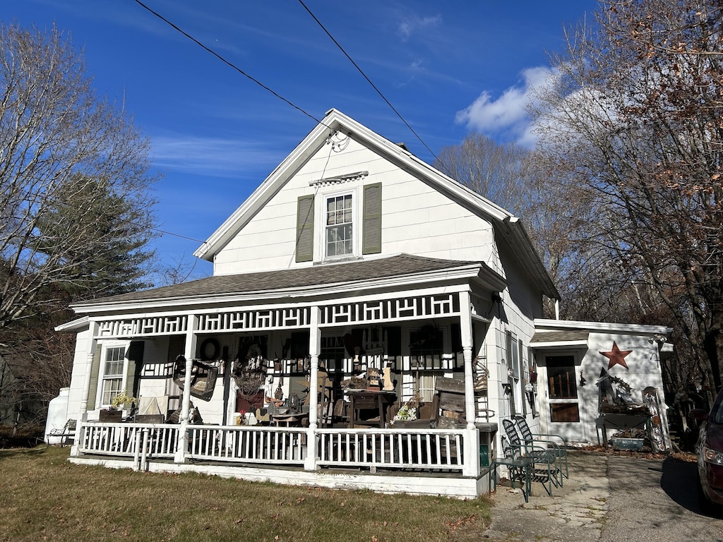 rear view of property with covered porch and roof with shingles