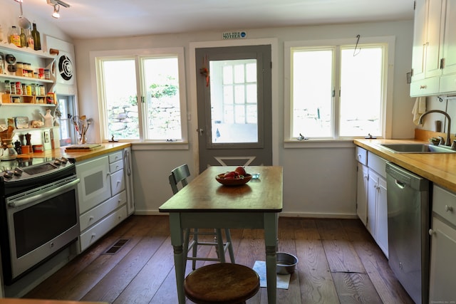 kitchen with dark wood-type flooring, appliances with stainless steel finishes, white cabinetry, and sink