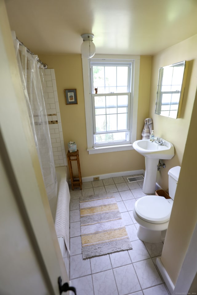 bathroom featuring toilet, shower / tub combo with curtain, and tile patterned floors