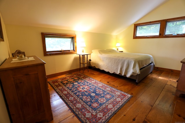 bedroom with multiple windows, vaulted ceiling, and hardwood / wood-style floors