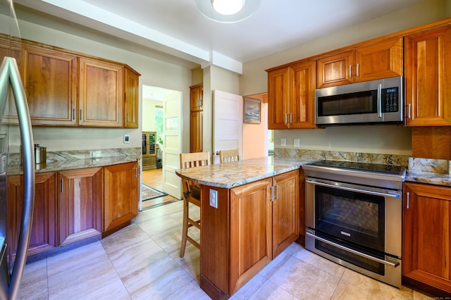 kitchen with stainless steel appliances, a kitchen breakfast bar, light stone countertops, and kitchen peninsula