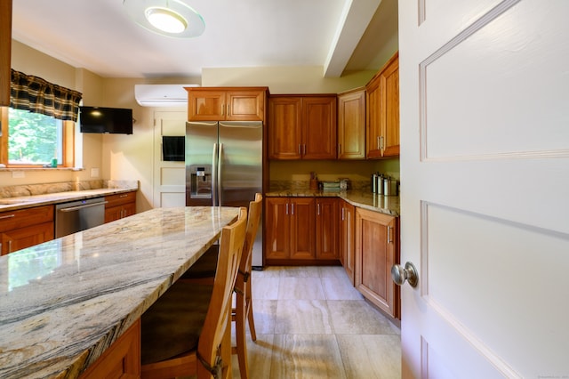 kitchen featuring a breakfast bar area, light stone counters, an AC wall unit, and appliances with stainless steel finishes