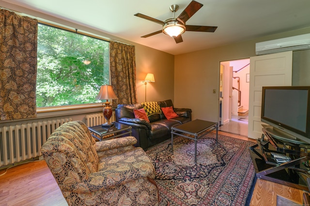 living room featuring radiator heating unit, hardwood / wood-style flooring, an AC wall unit, and ceiling fan