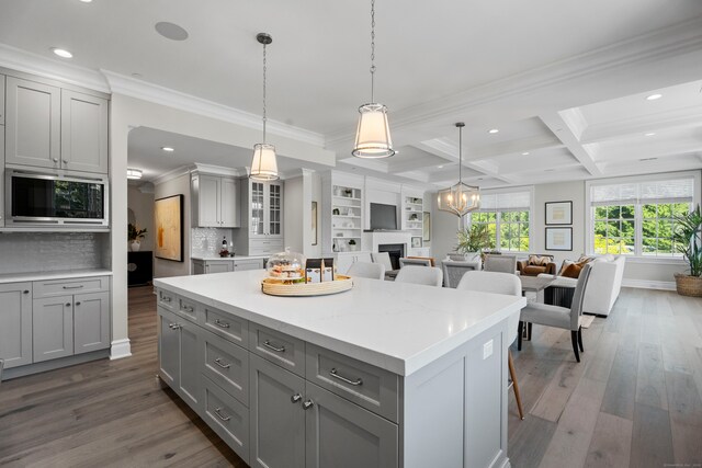 kitchen featuring coffered ceiling, stainless steel microwave, wood-type flooring, and gray cabinetry