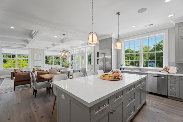 kitchen with coffered ceiling, stainless steel appliances, hardwood / wood-style flooring, and pendant lighting