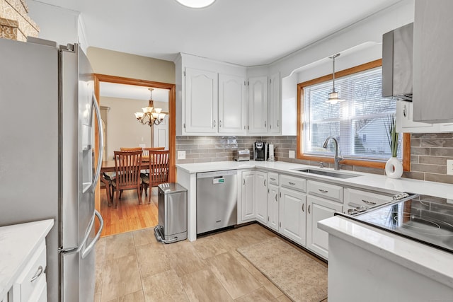 kitchen featuring a chandelier, stainless steel appliances, light countertops, and a sink