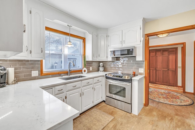 kitchen featuring a sink, backsplash, appliances with stainless steel finishes, and white cabinetry