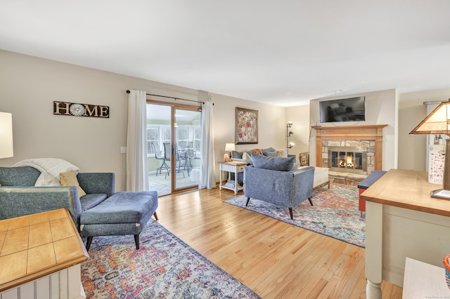 living area with a stone fireplace and light wood-style flooring