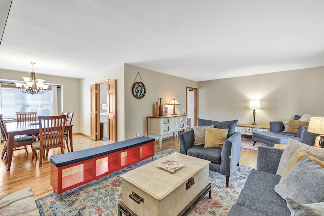 living area featuring baseboards, a notable chandelier, and light wood finished floors