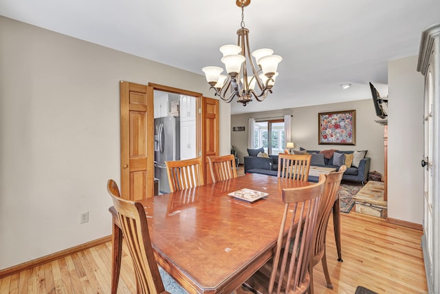 dining room with baseboards, an inviting chandelier, and light wood finished floors