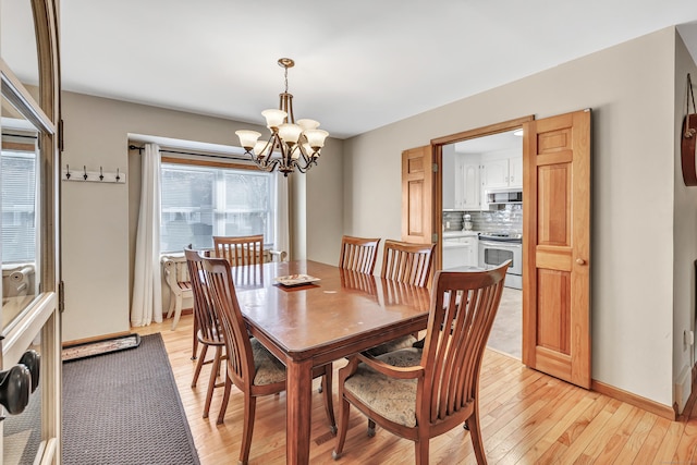 dining space featuring light wood-style floors, baseboards, and a chandelier