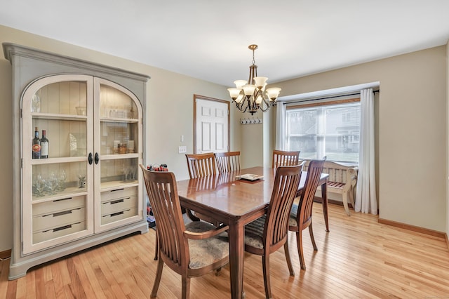 dining area with an inviting chandelier, light wood-style floors, and baseboards