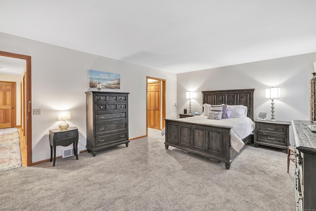 bedroom with visible vents, light colored carpet, baseboards, and connected bathroom