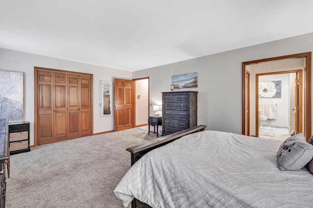 carpeted bedroom with a closet, ensuite bathroom, and baseboards