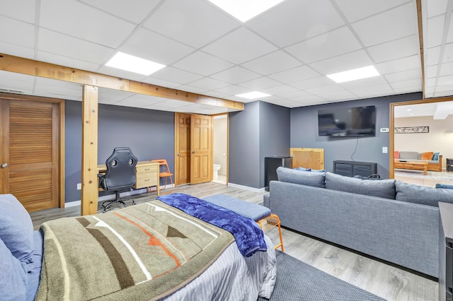 bedroom featuring wood finished floors, baseboards, and a drop ceiling