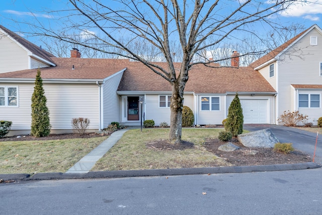 view of front of property featuring a front lawn, aphalt driveway, roof with shingles, a chimney, and a garage