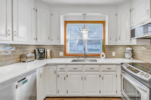 kitchen with light countertops, decorative backsplash, stainless steel appliances, white cabinetry, and a sink