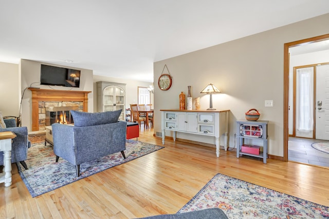 living area with visible vents, a fireplace, baseboards, and wood finished floors