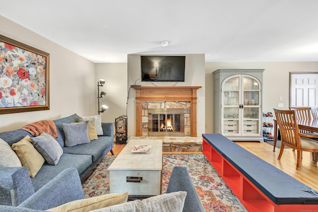 living room with a stone fireplace and wood finished floors