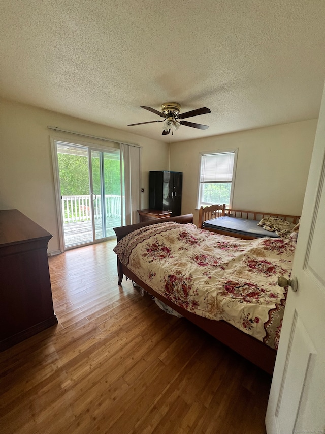 bedroom featuring ceiling fan, wood-type flooring, a textured ceiling, and access to exterior