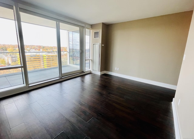 spare room featuring baseboards, dark wood-style flooring, visible vents, and floor to ceiling windows