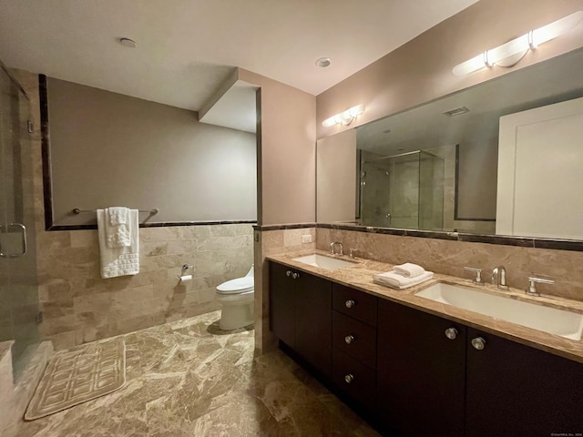 bathroom with toilet, double vanity, tile walls, and a sink