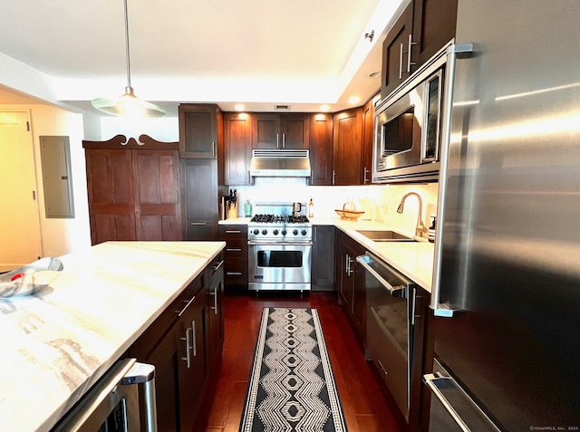 kitchen with decorative light fixtures, electric panel, dark hardwood / wood-style floors, sink, and premium appliances