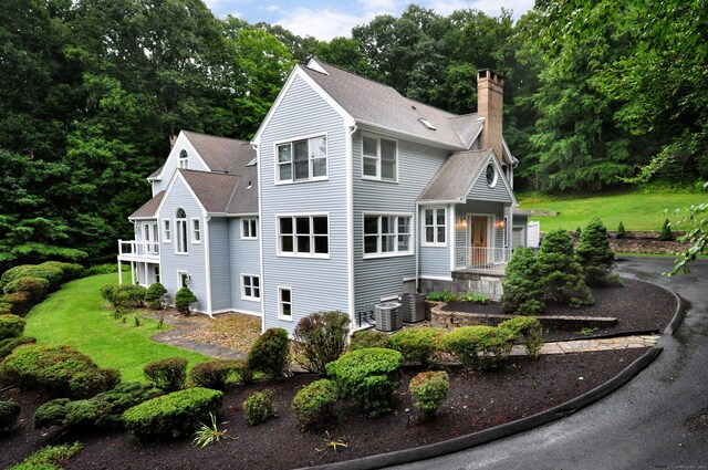 view of front of property with a balcony, a front lawn, and central AC