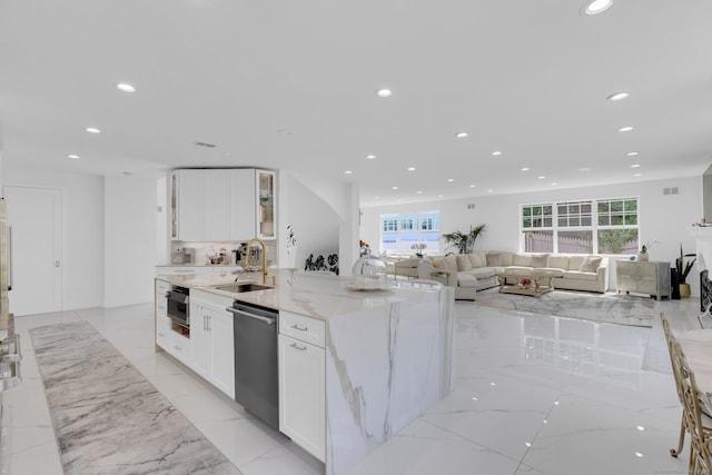 kitchen with stainless steel dishwasher, light stone counters, sink, and white cabinets