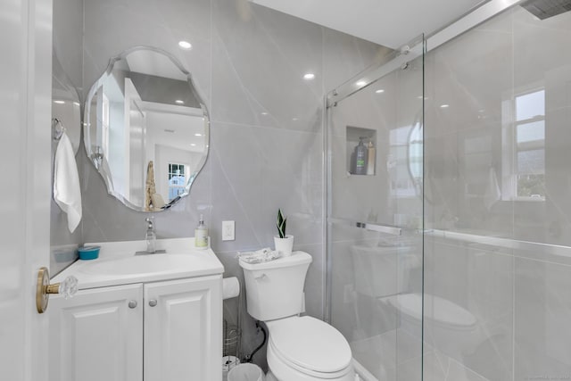 bathroom with vanity, toilet, walk in shower, and tile walls