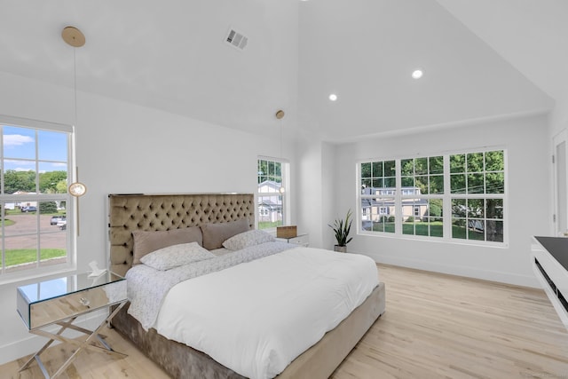 bedroom with multiple windows, high vaulted ceiling, and light hardwood / wood-style floors