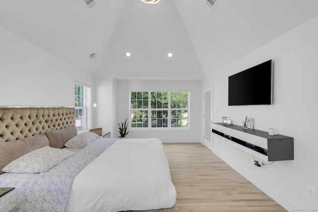 bedroom with light wood-type flooring, multiple windows, and high vaulted ceiling