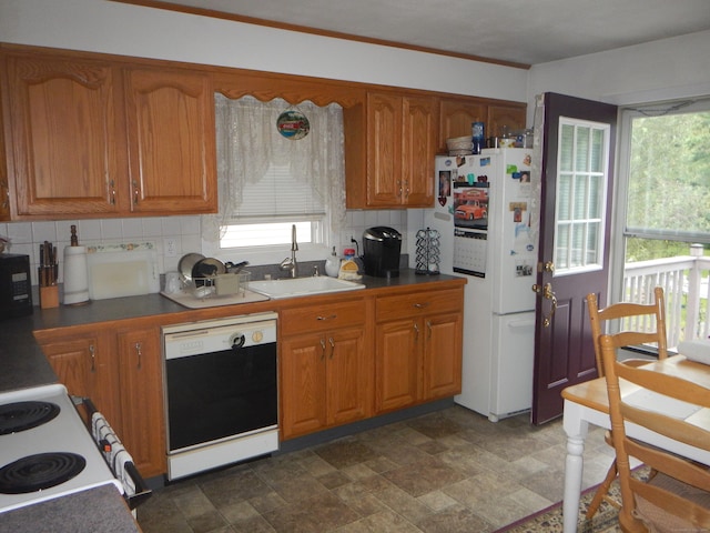 kitchen featuring black dishwasher, white fridge, sink, backsplash, and crown molding