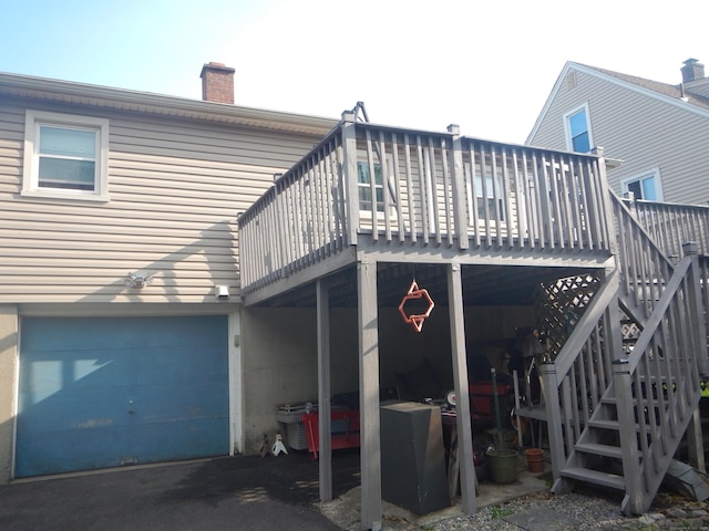 rear view of property with a garage and a wooden deck