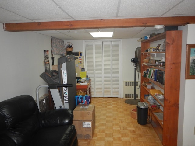 interior space featuring light parquet floors, a drop ceiling, and radiator