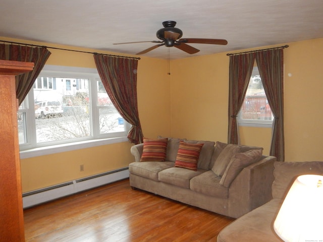 living room with baseboard heating, light hardwood / wood-style floors, plenty of natural light, and ceiling fan