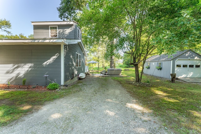 view of side of home featuring a jacuzzi, a garage, an outdoor structure, and central AC