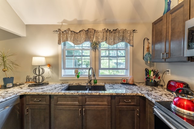 kitchen featuring dark brown cabinetry, sink, light stone counters, appliances with stainless steel finishes, and lofted ceiling