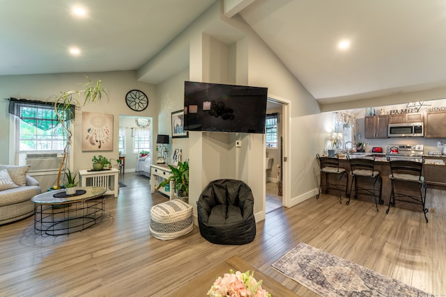 living room with light hardwood / wood-style floors, cooling unit, and high vaulted ceiling