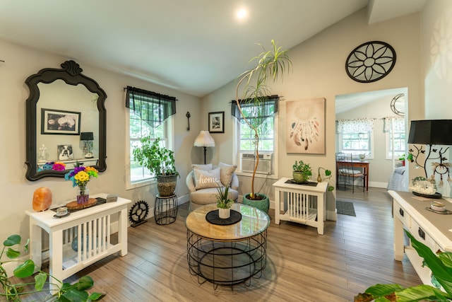 living area with hardwood / wood-style floors, lofted ceiling, and cooling unit