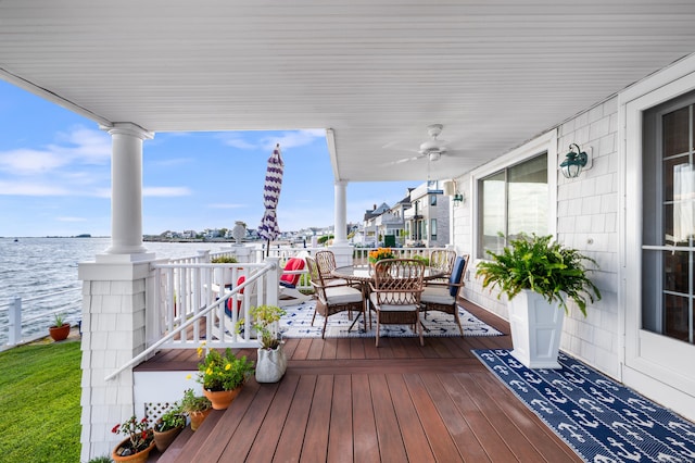 wooden terrace with ceiling fan, a water view, and covered porch