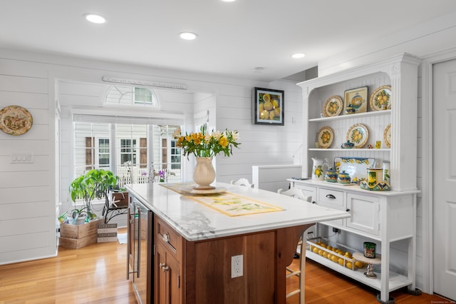 kitchen featuring beverage cooler, light hardwood / wood-style floors, and wood walls