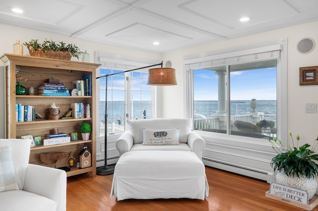 sitting room with baseboard heating, a water view, and wood-type flooring