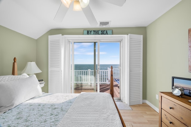 bedroom featuring ceiling fan, light wood-type flooring, access to exterior, lofted ceiling, and a water view