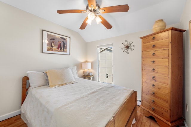 bedroom featuring ceiling fan, lofted ceiling, a baseboard heating unit, and hardwood / wood-style floors