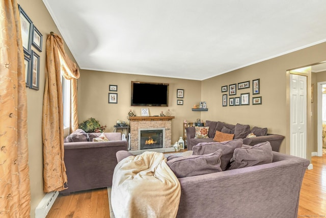 living room featuring light wood-type flooring, ornamental molding, a baseboard radiator, and a stone fireplace