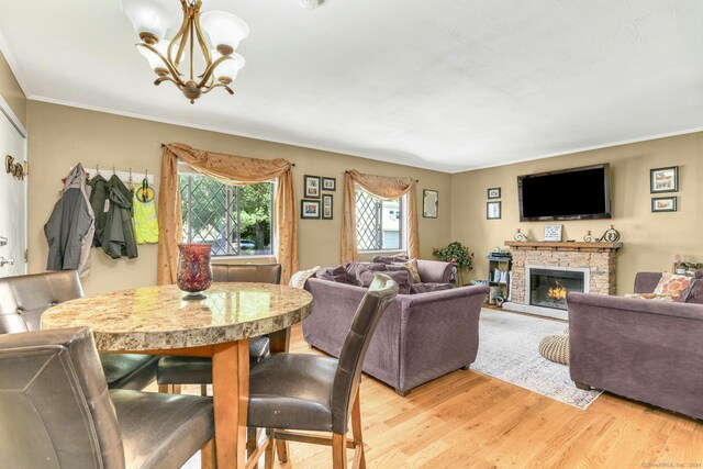 dining space with a fireplace, light hardwood / wood-style flooring, crown molding, and a notable chandelier